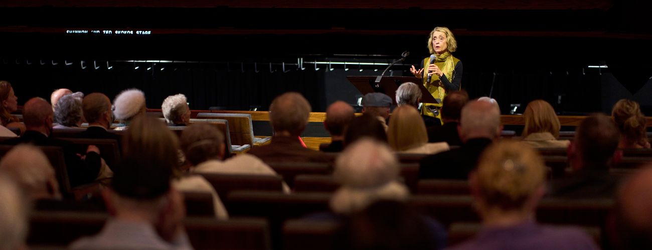 Woman giving a talk in front of an opera crowd at the WInspear Opera House - Pre-Opera Talks with opera experts at The Dallas Opera in Texas