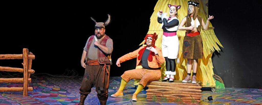 Humans dressed as animals singing and miming playing instruments in THE BREMEN TOWN MUSICIANS family opera